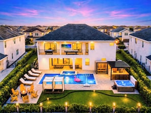 Une maison à deux étages avec une piscine, un espace salon extérieur et un jacuzzi.