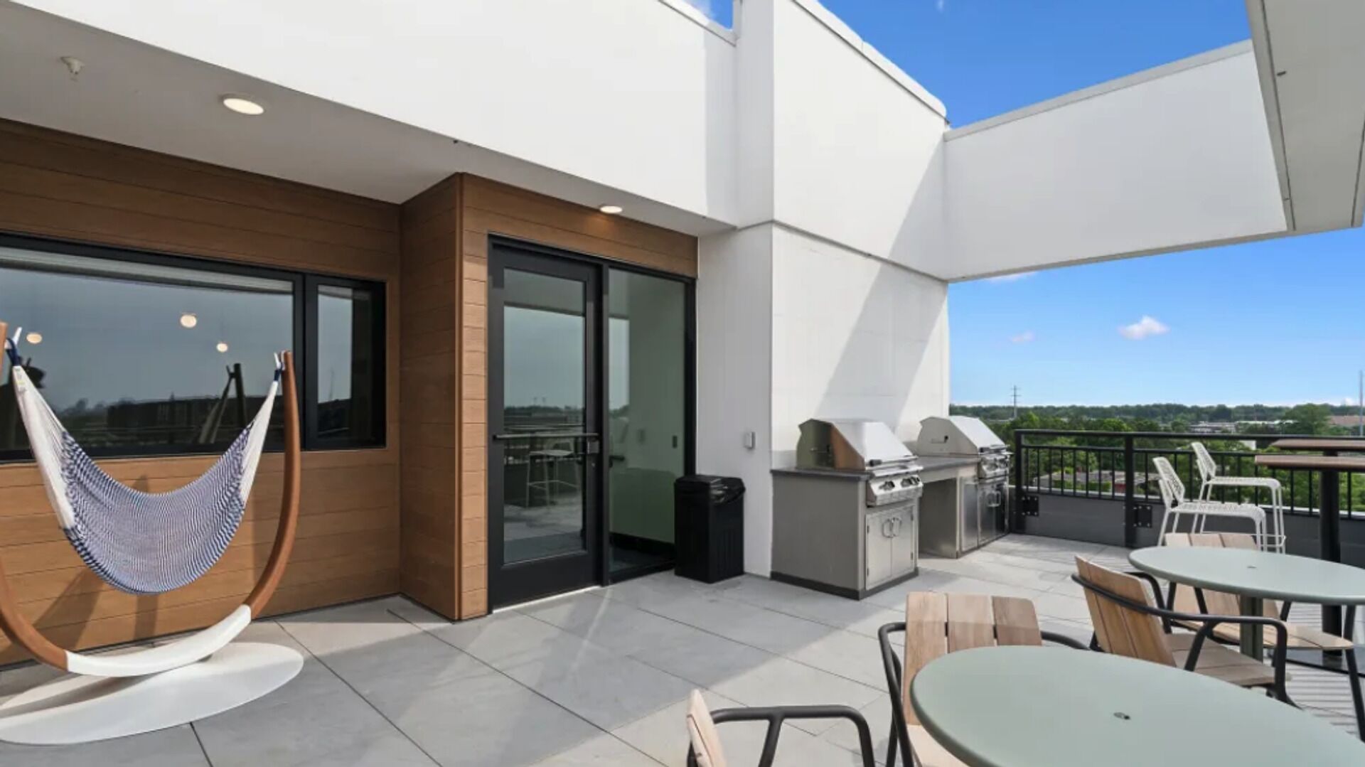 Een balkon met een hangmat, zitplaatsen buiten en een barbecue.