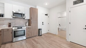 Een moderne keuken met roestvrijstalen apparatuur, houten kastjes en een betegelde spatwand.