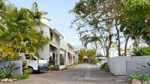 Una calle residencial con casas, coches aparcados y abundante vegetación.