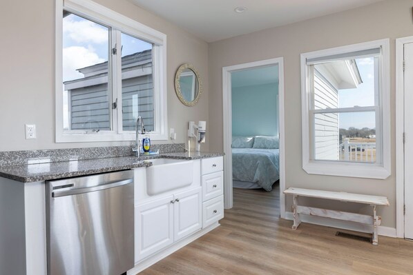 A modern kitchen with granite countertops, stainless steel appliances, and a view to the bedroom.