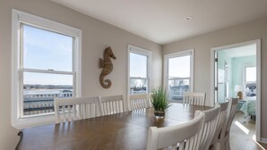 A dining room with a large wooden table, white chairs, and a seahorse wall decoration. - Amazing 10 Bedroom Compound on the Water with 6 Bedroom Home & 4 Studio Cottages (Stonington)