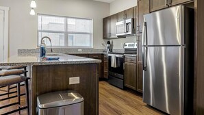 A modern kitchen with a stainless steel refrigerator, built-in oven, microwave, and granite countertop. - Landing | Stunning 2BD, Clubhouse, Gym (Indianapolis)