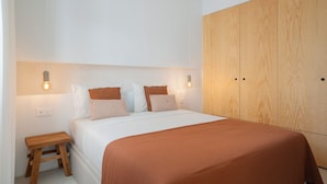 A bedroom with a bed, wooden wardrobe, and bedside lamps. - In Funchal city centre - AL'gria II (Funchal)