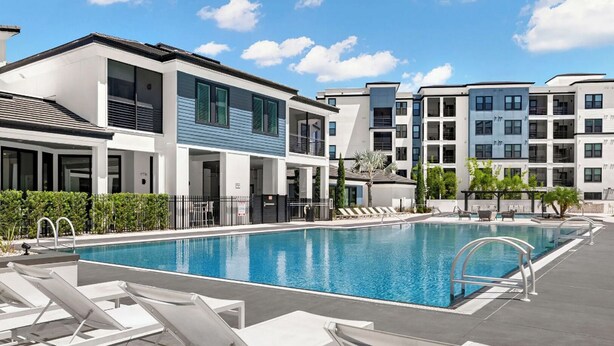 A modern hotel with a swimming pool, sun loungers, and a landscaped garden. - Landing | Modern 2BD, Gym, Pool (Tampa)