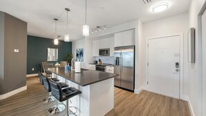 Een moderne keuken met een centraal eiland, roestvrijstalen apparatuur en hanglampen.