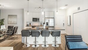 Une cuisine moderne dotée d’un îlot central, de tabourets de bar et d’un coin salon avec un banc bleu.