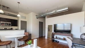 Un salon moderne comprenant un coin cuisine, une table à manger et un téléviseur à écran plat.