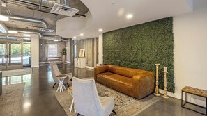 A spacious lobby with a leather sofa, a white armchair, and a patterned rug.