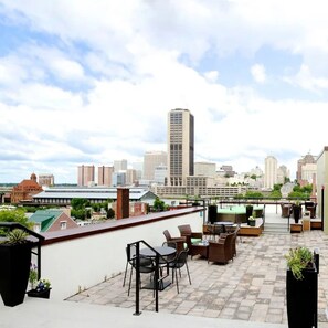 Una terrazza sul tetto con arredi da esterno, uno skyline cittadino sullo sfondo e vista sul paesaggio urbano.