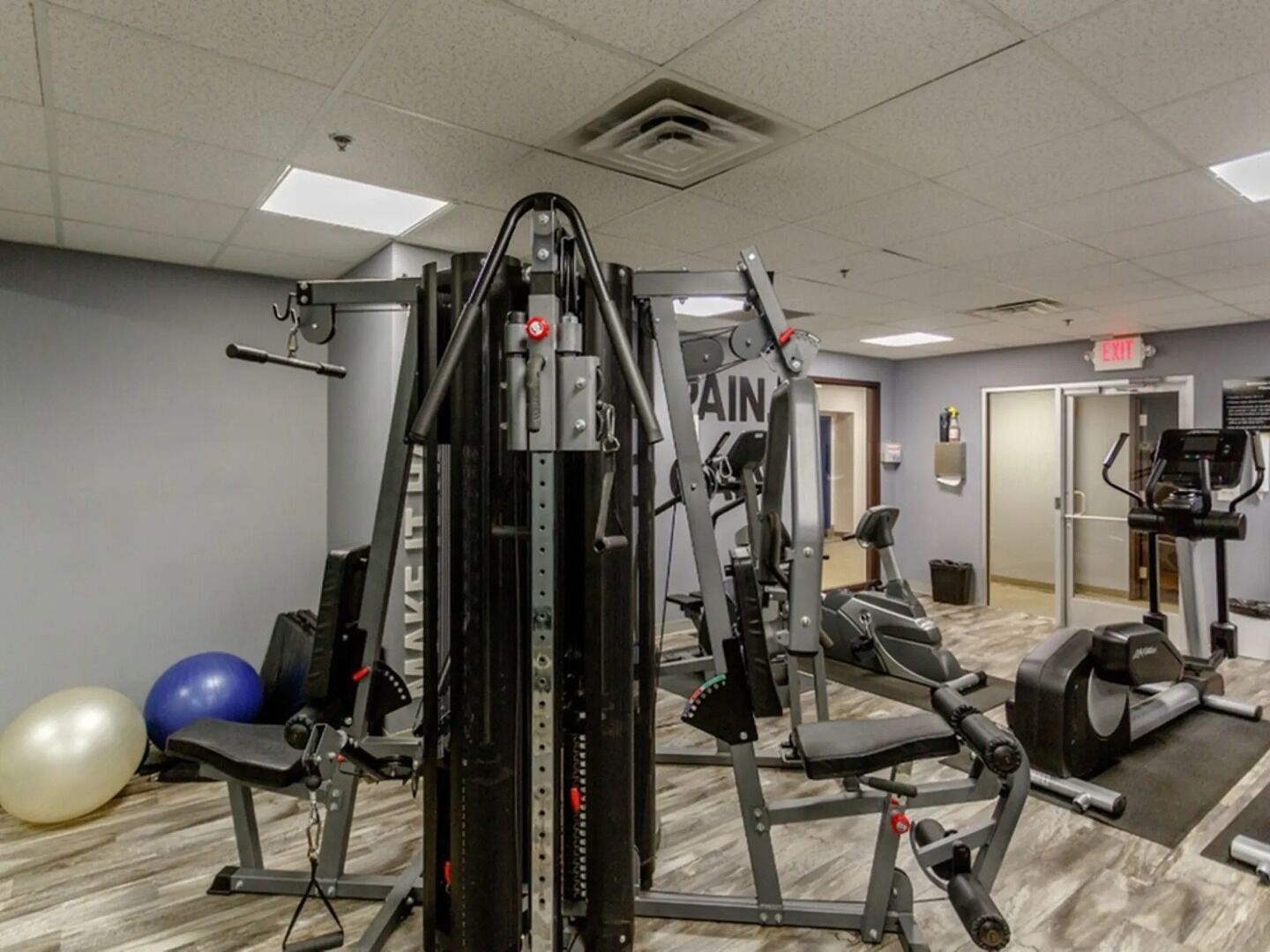 A gym with exercise equipment, a mirror, and exercise balls.