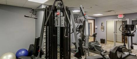A gym with exercise equipment, a mirror, and exercise balls.