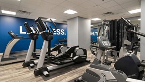Un gimnasio con cintas de correr, elípticas y equipo de pesas.
