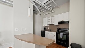 A modern kitchen with white cabinets, a black stove, and a wooden countertop.