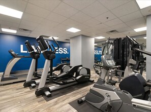 Un gimnasio con cintas de correr, elípticas y equipo de pesas.
