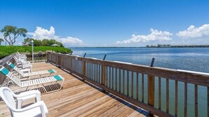 Une terrasse en bois avec des chaises longues et une vue sur une étendue d’eau calme.