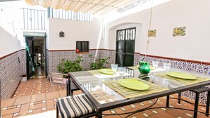 Eine Terrasse mit einem Glastisch, Stühlen und einer grünen Vase.