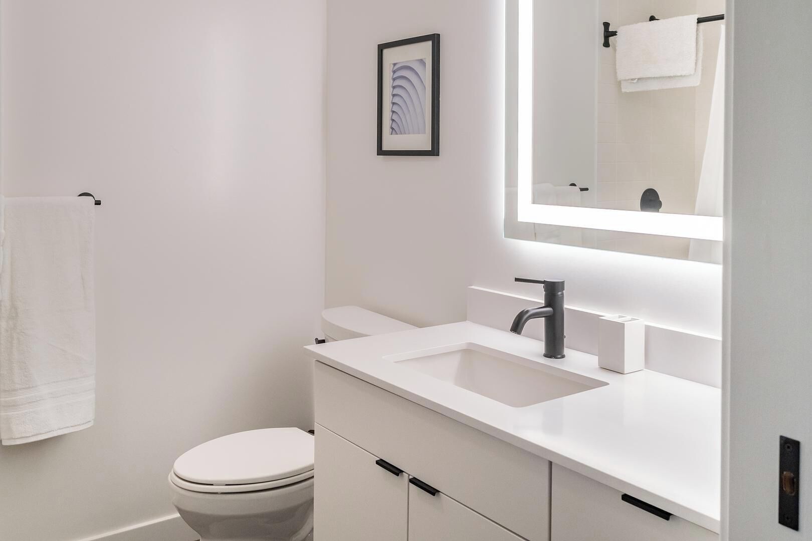 Une salle de bain moderne avec un lavabo blanc, un miroir et des toilettes.