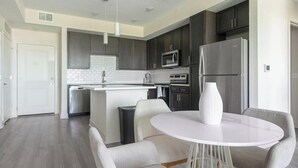 Une cuisine moderne avec des meubles de couleur sombre, des appareils en acier inoxydable et un ßlot central doté de siÚges.