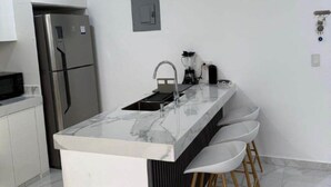 A modern kitchen with a central island, stainless steel appliances, and bar stools.