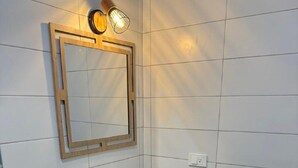 A modern bathroom with a white sink, wooden vanity, and a mirror with two wall-mounted lights.