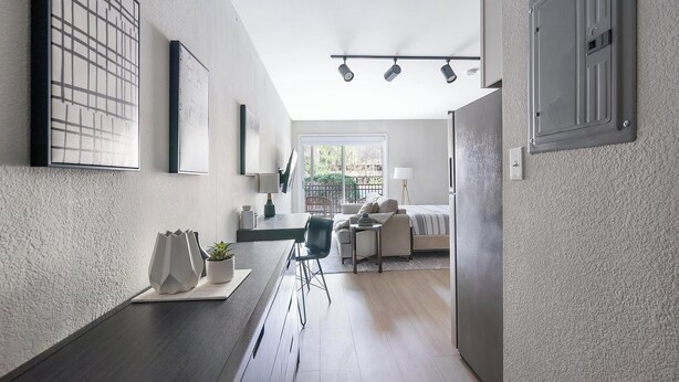Eine moderne Küche mit dunkler Arbeitsplatte, ein Essbereich mit Tisch und Stühlen sowie ein Blick auf einen Balkon mit Geländer.