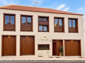 A building with a tiled roof, multiple windows, and a sign indicating 'MARICARME 12'.
