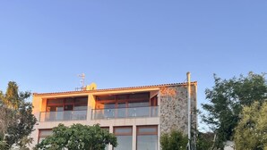 Un edificio de dos pisos con fachada de piedra, ventanas amplias y un balcón.