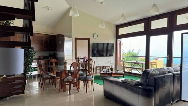 Amplia sala de estar con comedor, sofá y ventanas grandes que ofrecen vistas.