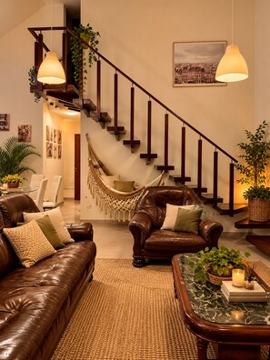A modern living room with a leather sofa, a coffee table, and a hammock.