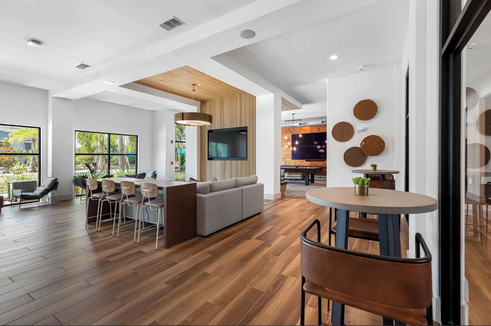 A modern interior with a dining area, a sofa, and a TV mounted on a wooden panel wall.