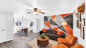 A modern living room with a sofa, two armchairs, a coffee table, and a dining area with a table and chairs. - • NEW • Walk to AT&T Stadium  and Globe Life Field • Rangers • Free parking (Arlington)
