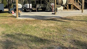 Um parque para veículos recreativos coberto, com vários RVS estacionados sob uma cobertura de metal, um reservatório de água e uma escada que leva a um andar superior.