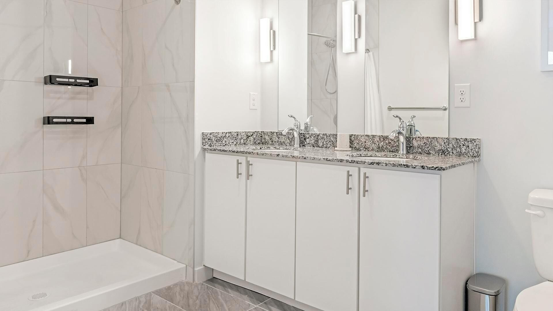 Une salle de bain moderne équipée d’une douche, de toilettes et d’un lavabo avec un miroir.