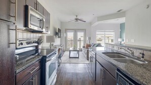 A modern kitchen with stainless steel appliances, a dining area with a sofa, and a view to the outside.