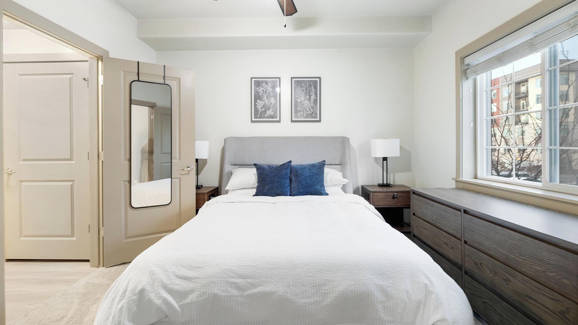Una camera da letto con un letto, comodini, una cassettiera, uno specchio e due quadri appesi al muro.