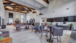 Een ruime woonkamer met een pooltafel, eethoek en een keuken op de achtergrond.