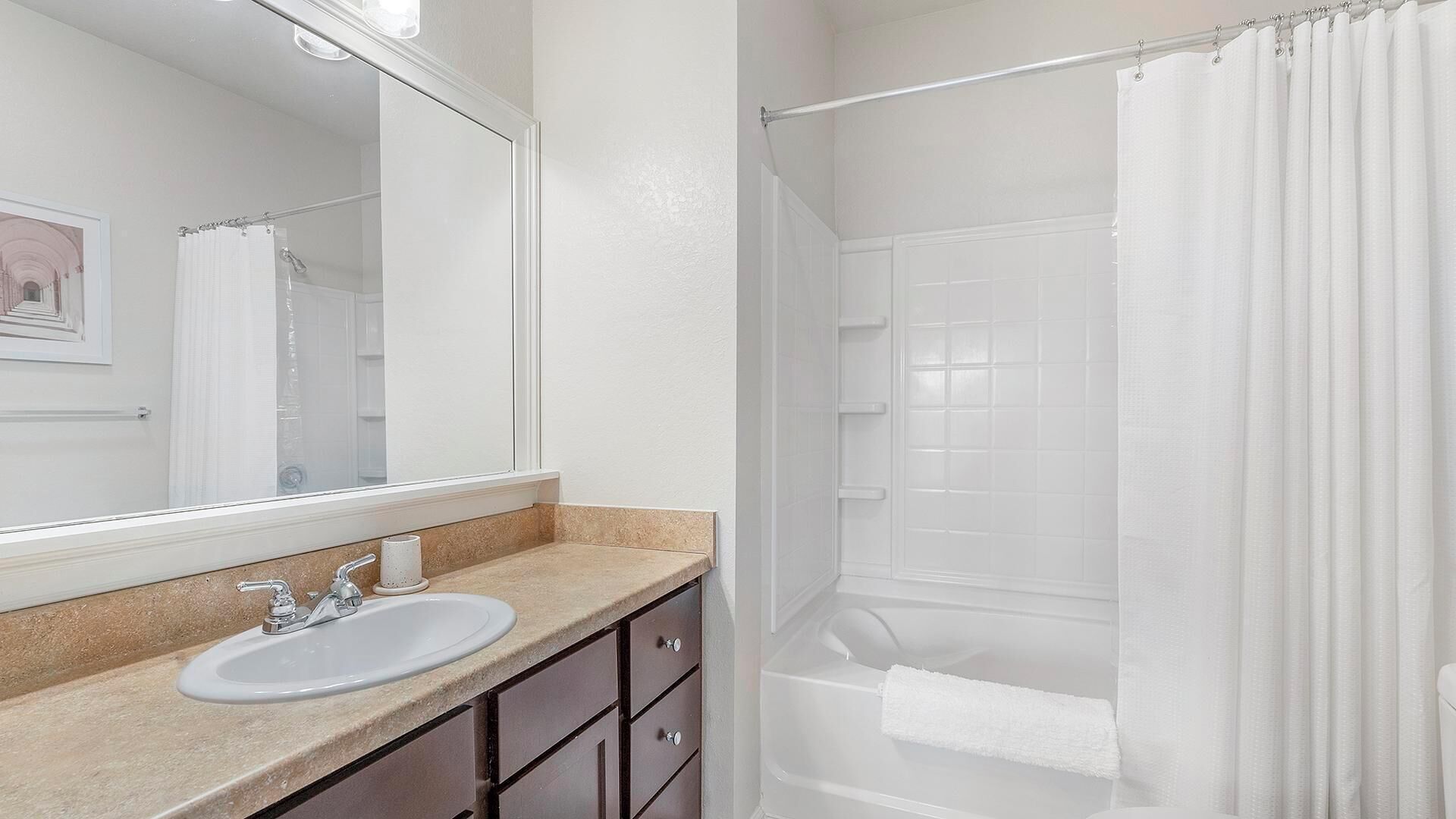 A bathroom with a sink, mirror, and shower curtain.