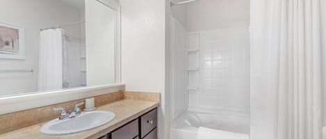 A bathroom with a sink, mirror, and shower curtain.