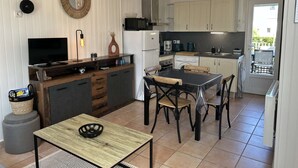 Cocina compacta con comedor, televisión y lámpara colgante.