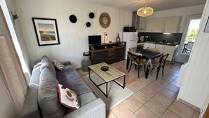 Un espacio habitable compacto con sofá, mesa de comedor y kitchenette.