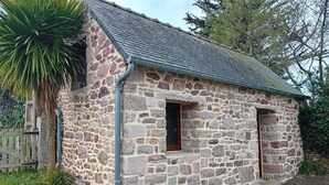 Un edificio de piedra con techo inclinado, una ventana pequeña y una puerta.