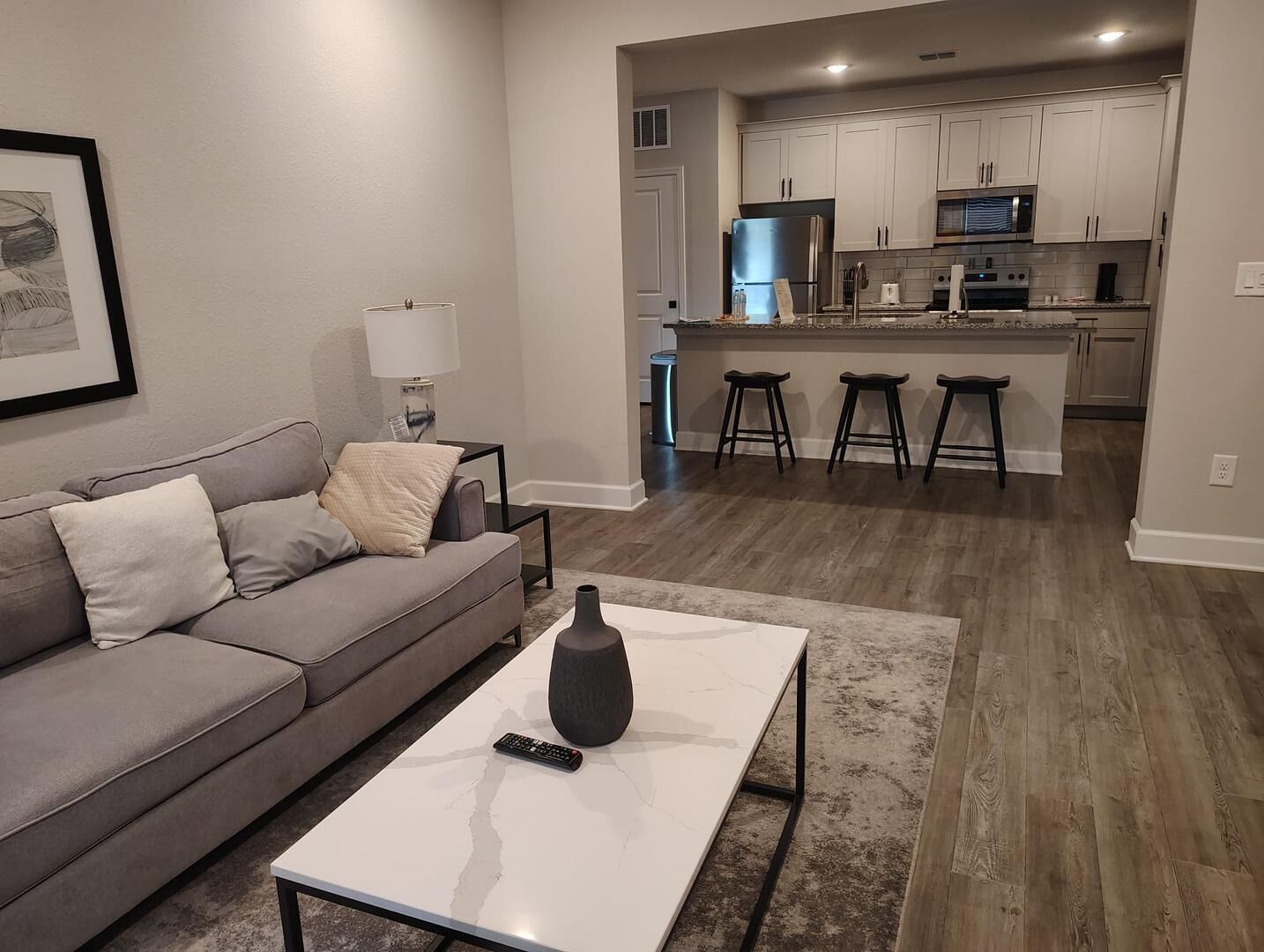 A modern living room with a grey sofa, a white coffee table, and a remote control on it.
