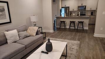 A modern living room with a grey sofa, a white coffee table, and a remote control on it.