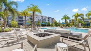Un área junto a la piscina con sillones de descanso, una chimenea y una pileta.