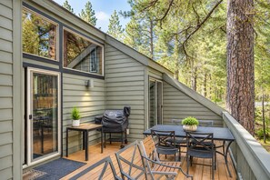 A deck with a table and chairs, a grill, and a potted plant.