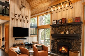 A cozy living room with a fireplace, mounted deer heads, and a television.