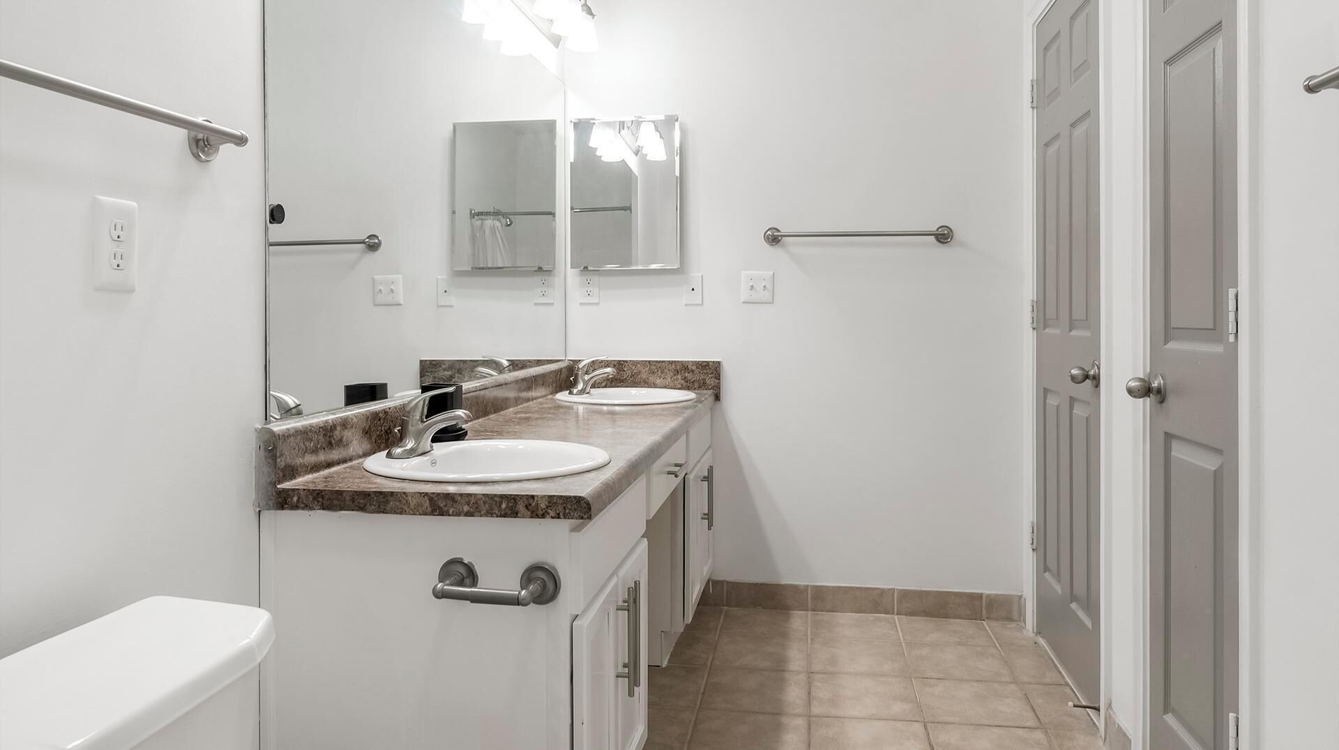 A bathroom with two sinks, a mirror, and a toilet.