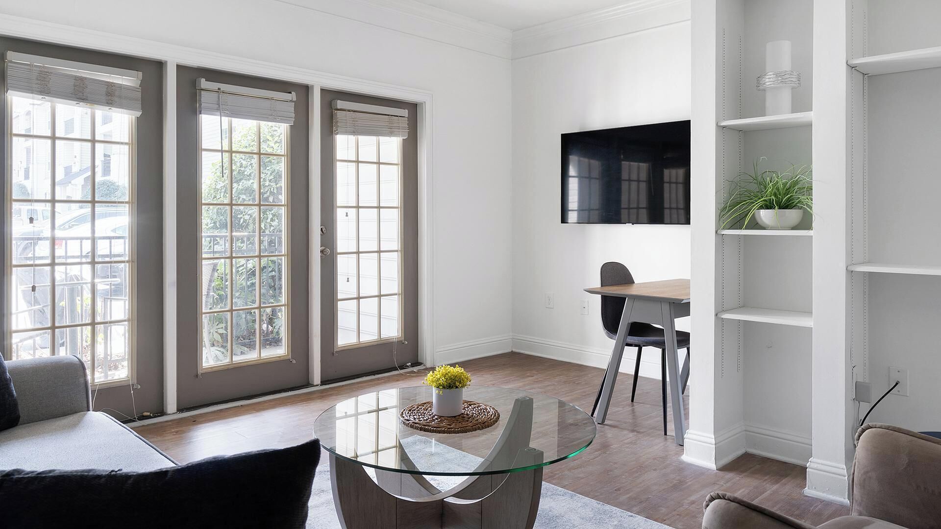 A modern living room with a glass coffee table, a sofa, and a dining area with a chair.