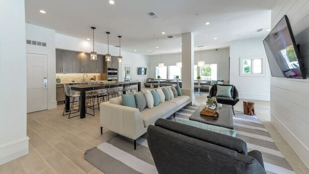 A spacious living area with a sofa, a coffee table, and a TV mounted on the wall. - Landing | Incredible 2BD, Pool, Game Room (Buckhead)